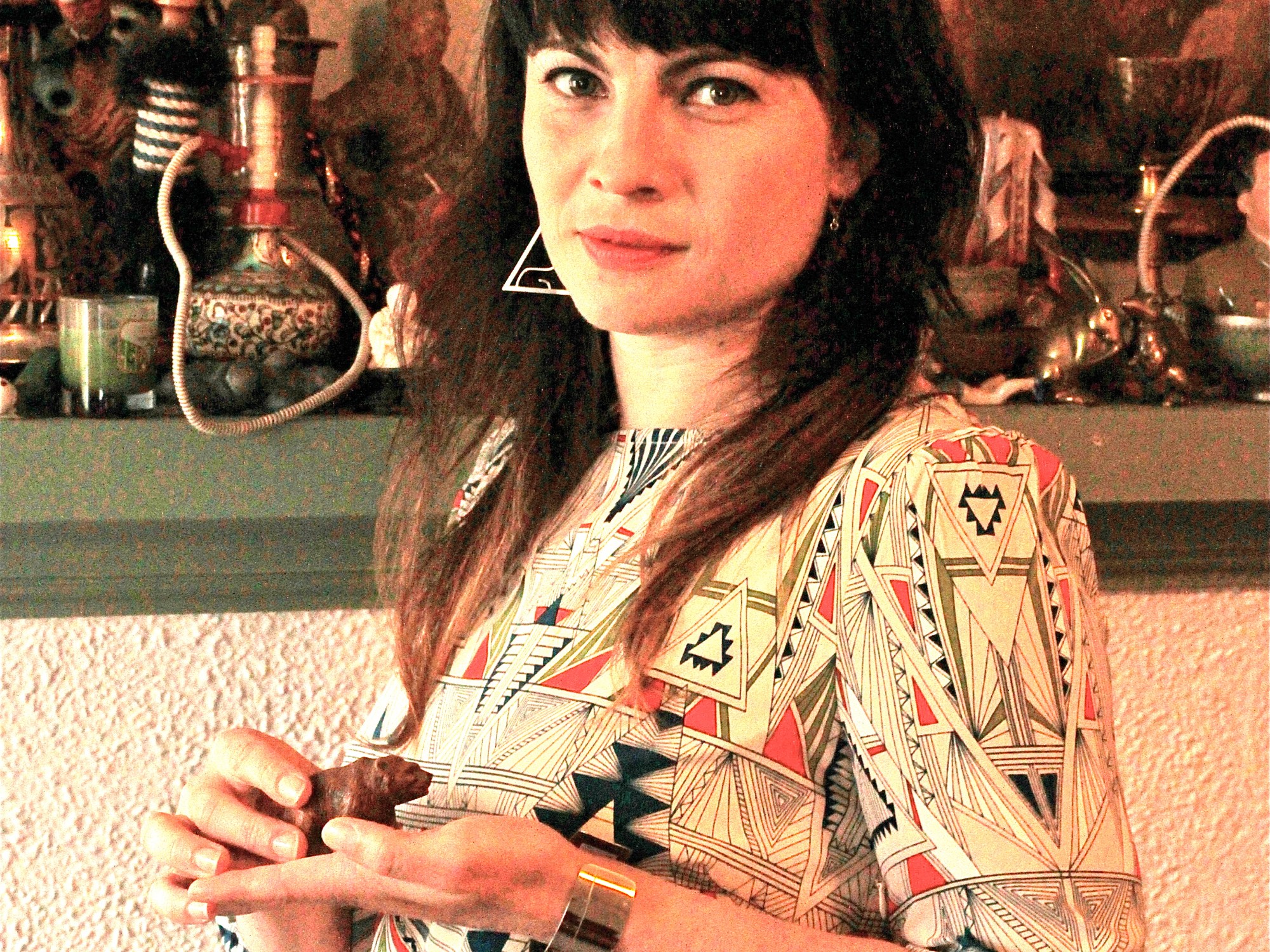 A dark haired woman holding the a bear shaped knickknack.