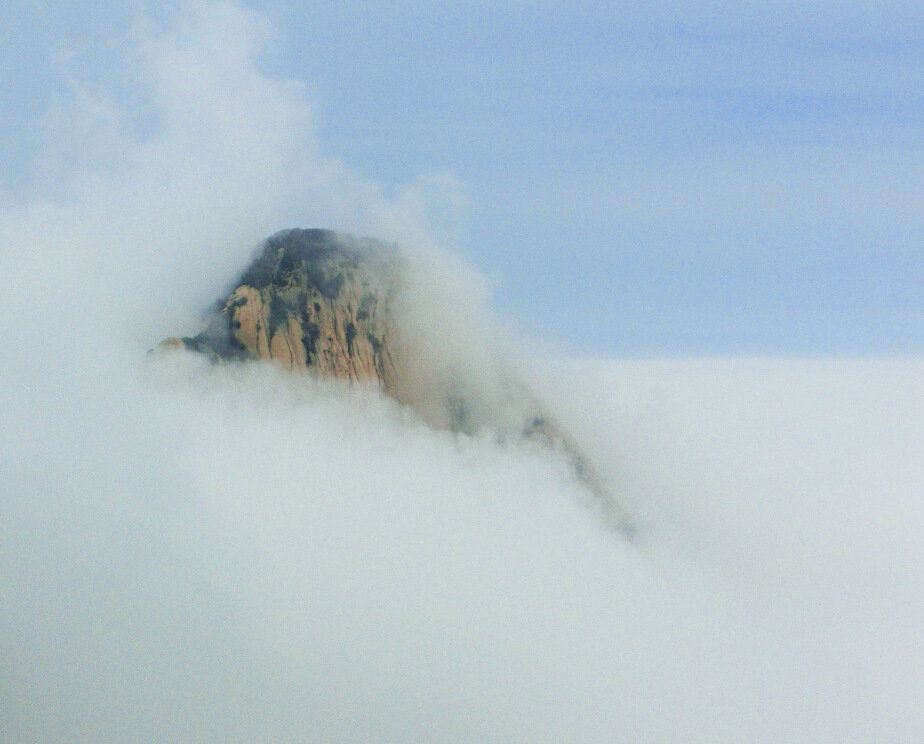 a close up of clouds pushing over a mountain peak in China.